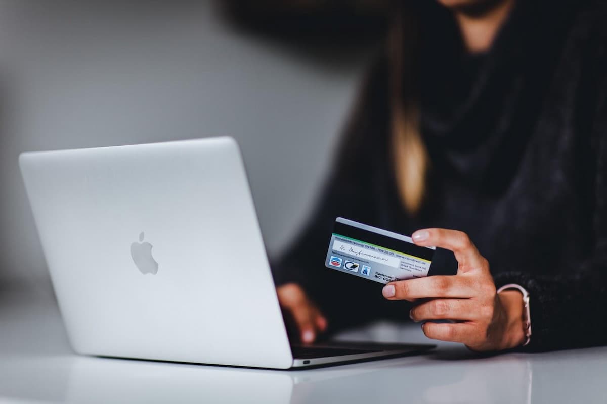 A person holding a credict card sitting in front of the computer